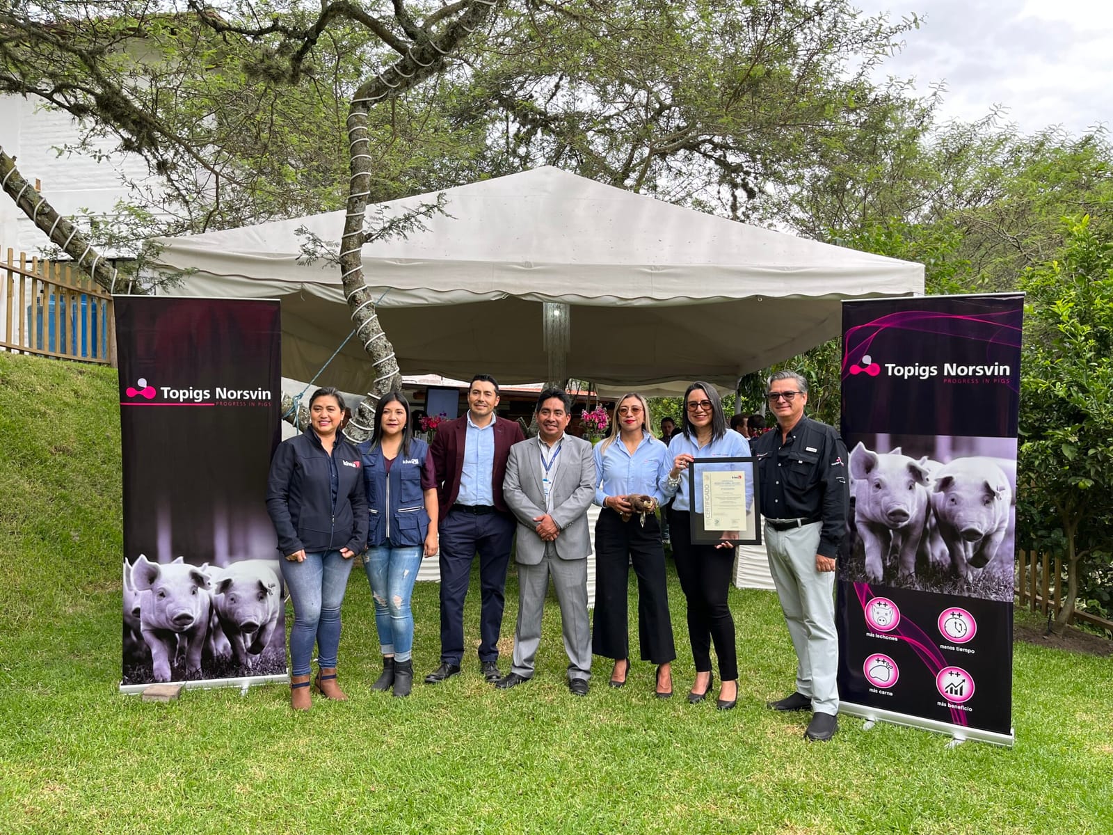 Entrega do certificado Welfair à equipe da Topigs Norsvin Ecuador, ao lado dos cartazes da marca