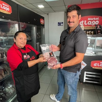 Una asesora entrega un producto empacado a un cliente dentro de un local de Market d'Lago