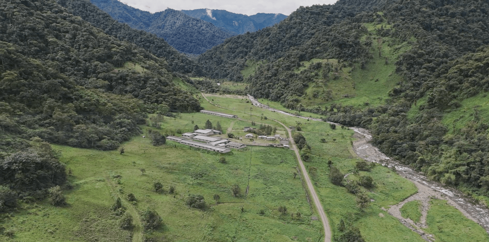 Vista aérea das instalações da Agroindustrias González em um vale amazônico, cercadas de floresta e montanhas